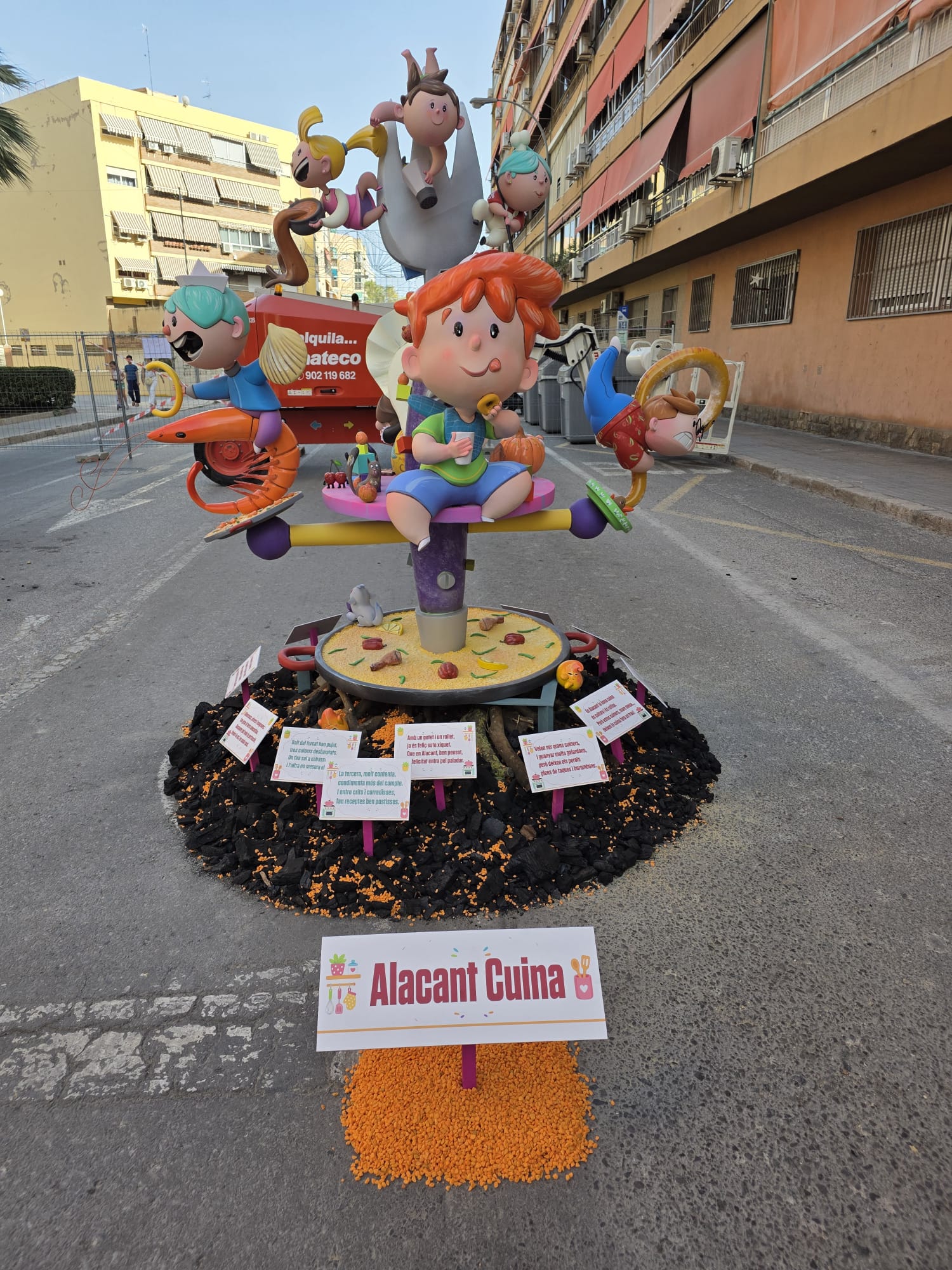 Vista frontal de la Hoguera Infantil Princesa Mercedes 2026 con decoración realizada mediante carbón vegetal, piedra decorativa naranja y leña de naranjo integrado en la temática de la hoguera.